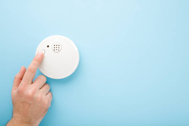Young man finger touching new white plastic smoke alarm. Light blue table background. Pastel color. Safety concept. Empty place for text. Young man finger touching new white plastic smoke alarm. Light blue table background. Pastel color. Safety concept. Empty place for text. smoke detector photos stock pictures, royalty-free photos & images