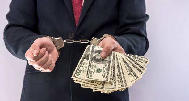 istock Bribe and corruption areest man who hold dollar in hand cuff, isolated 1242921997