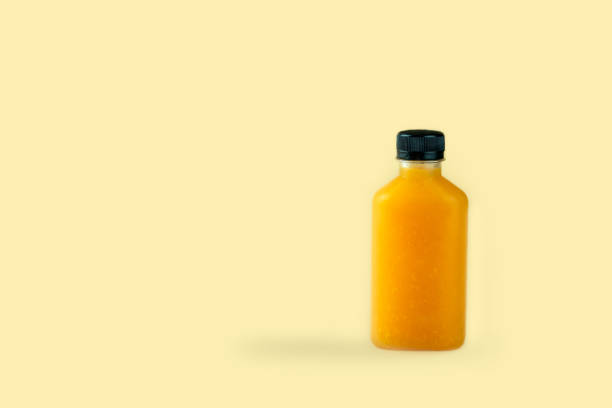 istock Natural pure orange juice packed in plastic bottles on yellow background 1242924255
