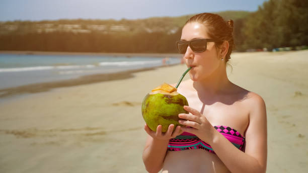 istock Young woman in sunglasses drinks coconut on the beach 1242930603