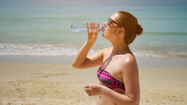 istock brunette lady stands on beach drinking water from bottle 1242930616