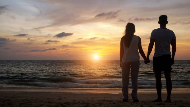 istock people silhouettes walking on beach coast to ocean at sunset 1242930665