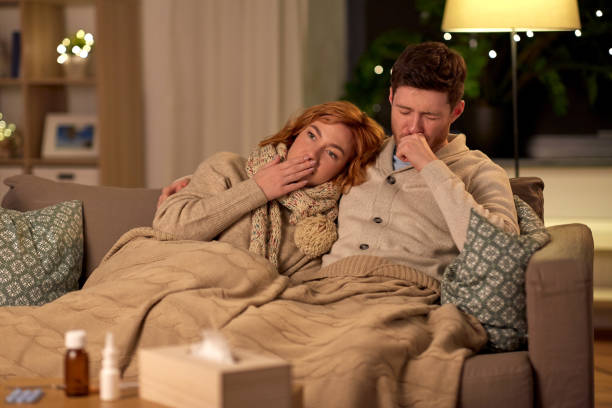istock sick young couple coughing at home 1242962111