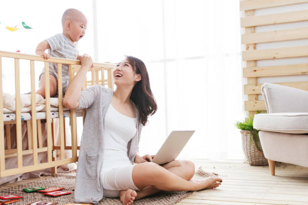 The young mother at home while the children use the computer - fotografia de stock