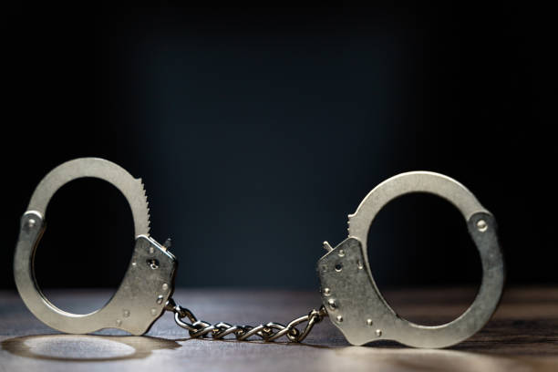 istock Shiny handcuffs on black background 1242963856