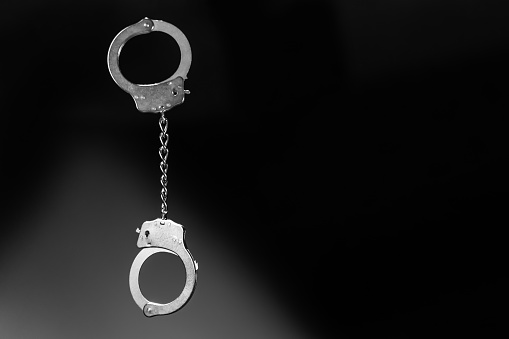 Shiny handcuffs on black background. The scene is situated in controlled studio environment in front of black background. Photo is taken with SONY AIII camera.