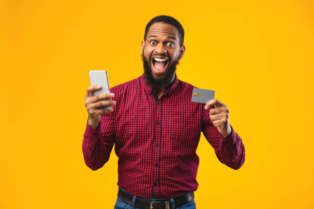 istock Black man holding credit card and cellphone at studio 1242972179