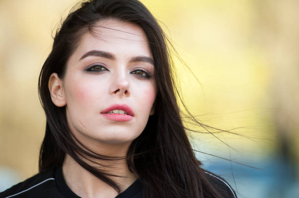 Close-up of charming young woman wearing light natural makeup. Cheerful pretty female with magnificent smile looking at camera with tenderness. Beauty concept