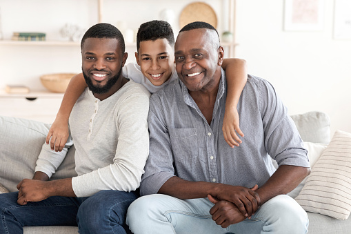 Black family, grandfather and father with girl in home, bonding and relax together. African grandpa, dad and happy child with care, love and smile, enjoying quality time and hug to embrace in house