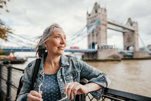 senior female tourist with blue eyes in london near tower bridge, traveling to uk after pandemic - women travel destinations london england tourist imagens e fotografias de stock