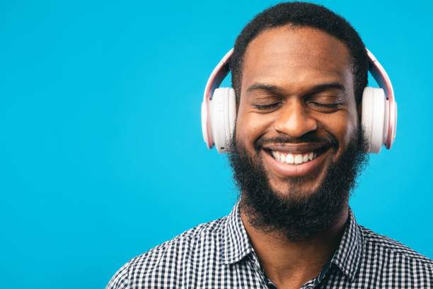 istock Smiling afro guy enjoying music using his headphones 1242987741