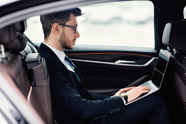 istock Young businessman using laptop in car 1242988359