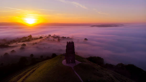 The famous Glastonbury Tor Early morning sunrise over Glastonbury Tor and the misty fields, Somerset. national trust photos stock pictures, royalty-free photos & images