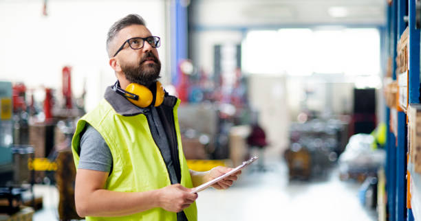 istock Technician or engineer with protective headphones standing in industrial factory. 1243008190