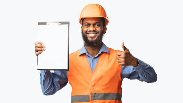 istock African Construction Worker Showing Folder Gesturing Thumbs-Up, White Background, Panorama 1243012222