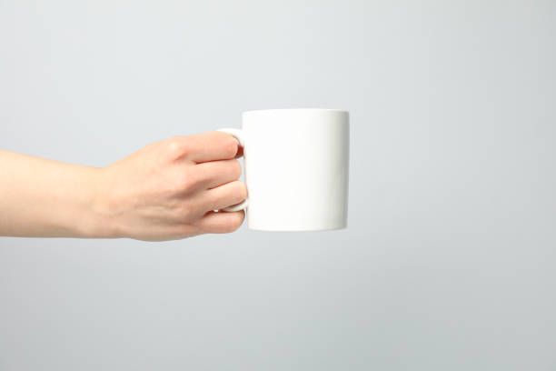 istock Female hand holding white cup on light gray background, space for text 1243026226