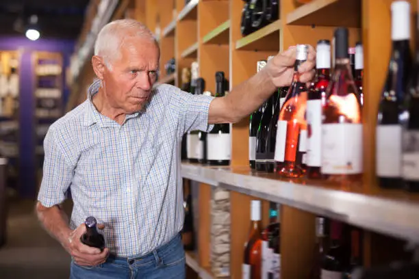 Adult man visiting winehouse in search of bottle of good wine