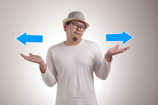 Asian man confused to decide a choice. Choose left or right direction arrow concept