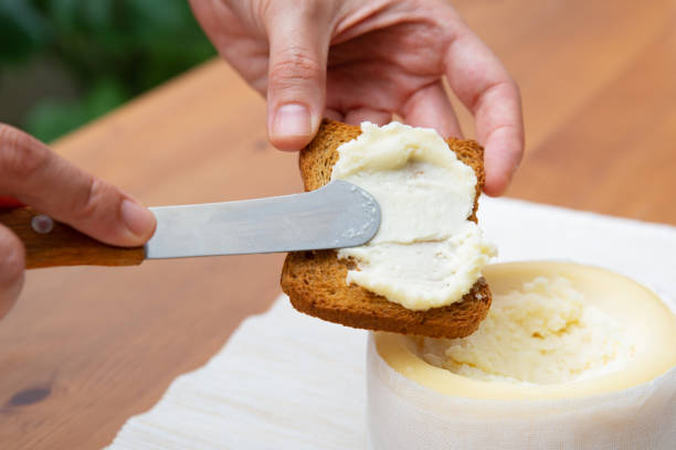 istock Female hands spreading soft cheese on toasted bread 1243045026