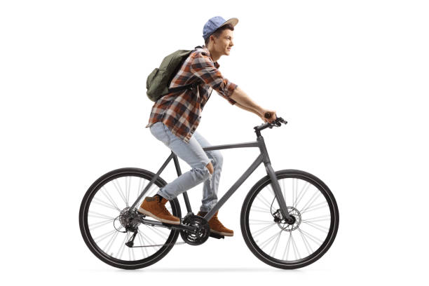 Profile shot of a male student riding a bicycle Profile shot of a male student riding a bicycle isolated on white background bicycle cycling school child stock pictures, royalty-free photos & images