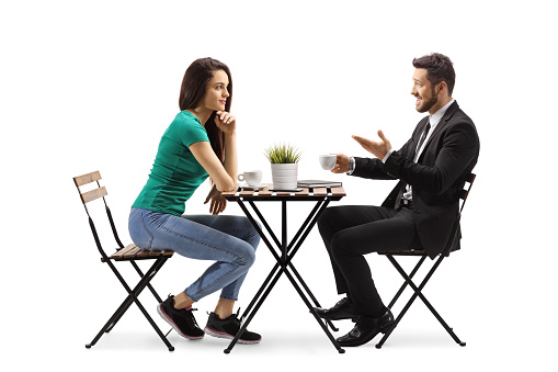 Young woman sitting at a wooden table and talking with a businessman isolated on white background