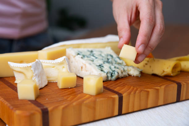 istock Hand taking piece of cheese from wooden board 1243064332