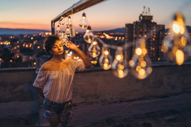 istock Young lonely woman with string light on rooftop 1243067770