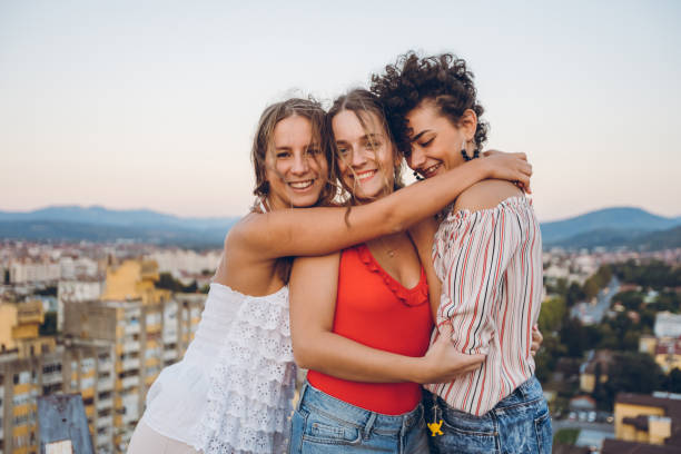 istock Three young women hugging on rooftop 1243070640