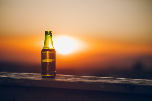 Close up picture of bottle of beer on the rooftop, at sunset.