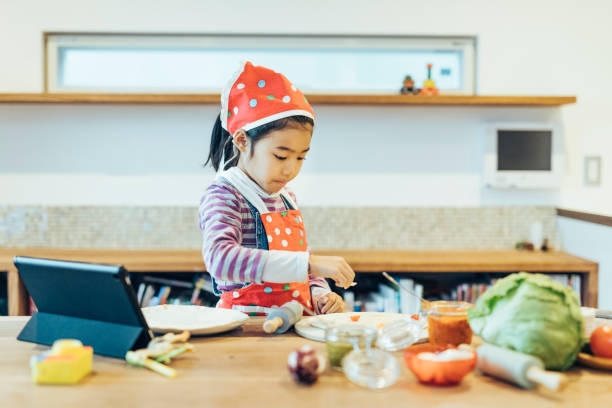 istock Small Girl Using Digital Tablet and Preparing a Pizza 1243084199