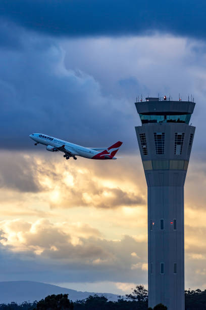 tour de contrôle de la circulation aérienne à l’aéroport international de melbourne avec un avion qantas décollant derrière. - airbus photos et images de collection