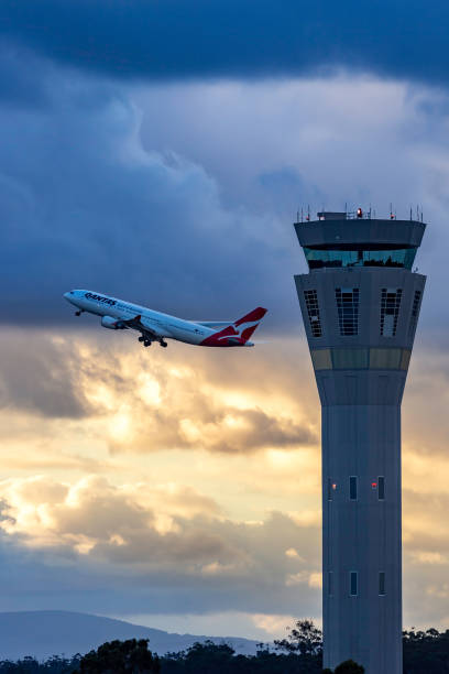 torre di controllo del traffico aereo all'aeroporto internazionale di melbourne con un aereo qantas che decolla alle spalle. - air traffic control tower foto e immagini stock