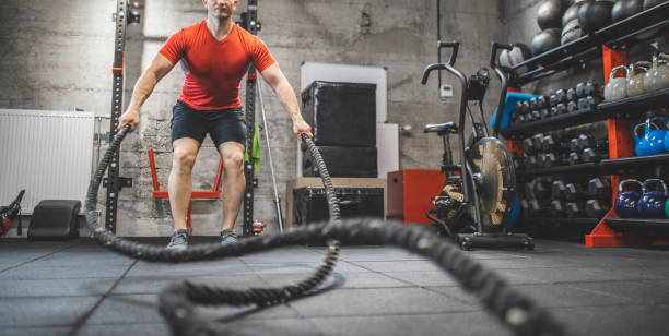 istock Athletic mid adult man doing some cross training exercises with a rope. Determined fit guy doing battle ropes exercise at the cross training gym. Handsome man training with effort 1243116156