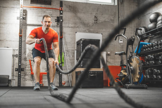 istock Athletic mid adult man doing some cross training exercises with a rope. Determined fit guy doing battle ropes exercise at the cross training gym. Handsome man training with effort 1243126630