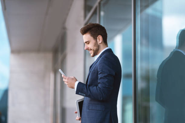 istock Confident young enterpreneur using his cellphone for online communication near business center 1243134359