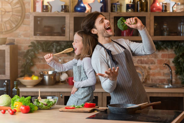 istock Kitchen Fun. Cheerful dad and his little daughter singing while cooking together 1243140878