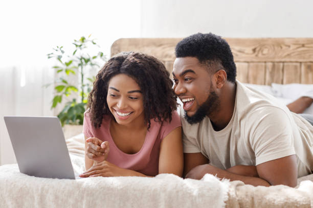 istock Funny african couple using laptop in bed 1243142033