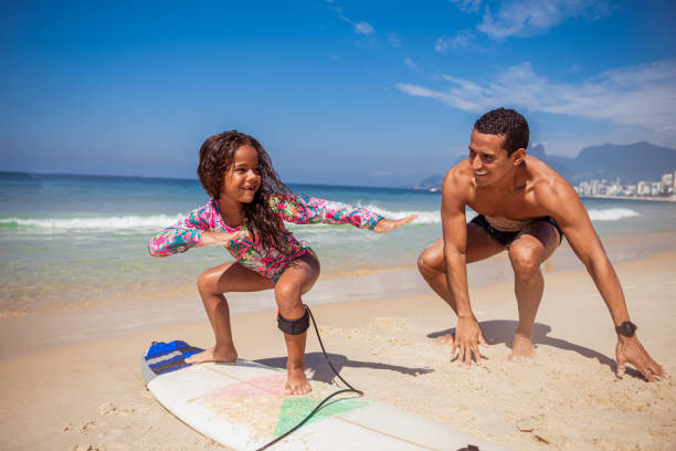 bambina brasiliana con suo padre che si prepara per il surf - surfing beach family father foto e immagini stock