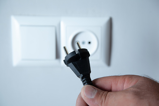 Electric plug in a hand on a white background