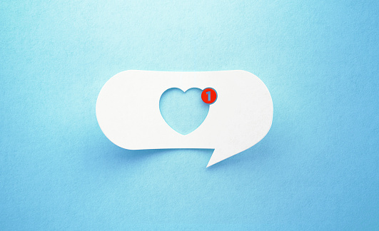 Heart shape drawn white chat bubble on blue background. Red number one is written on the chat bubble. Horizontal composition with copy space. Social media concept.