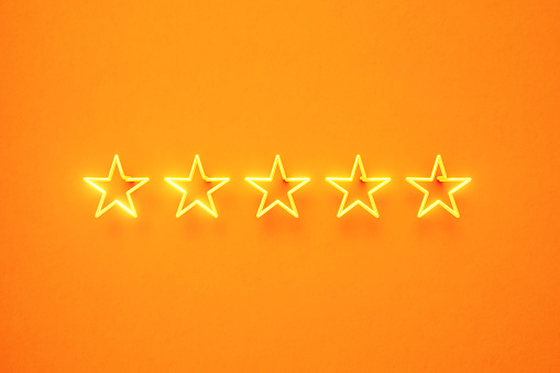 Five star written by yellow neon light on yellow background. Horizontal composition with copy space. Front view. First class and luxury concept.