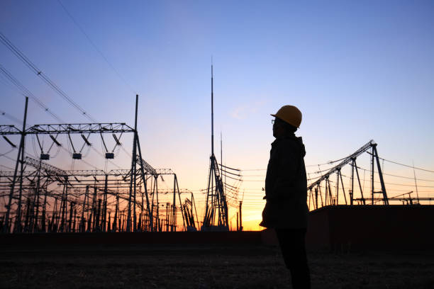 istock Electricity workers and pylon silhouette 1243194058