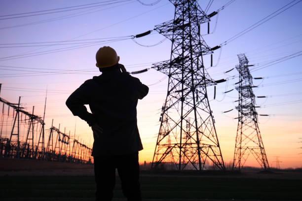istock Electricity workers and pylon silhouette 1243195696