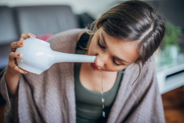 Cleaning procedure for the body One beautiful young woman using neti pot at home after yoga practice. human nose stock pictures, royalty-free photos & images