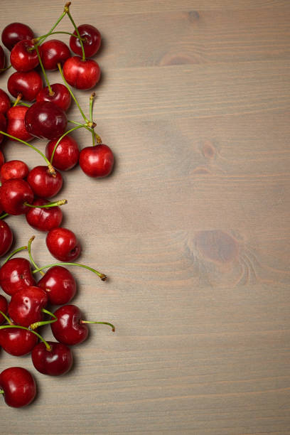 istock Green spring red cherries on wooden background selective focus cherry 1243239439