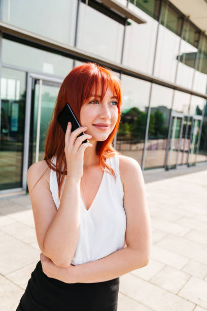 istock Red-haired girl talks on phone and looks at camera 1243244931