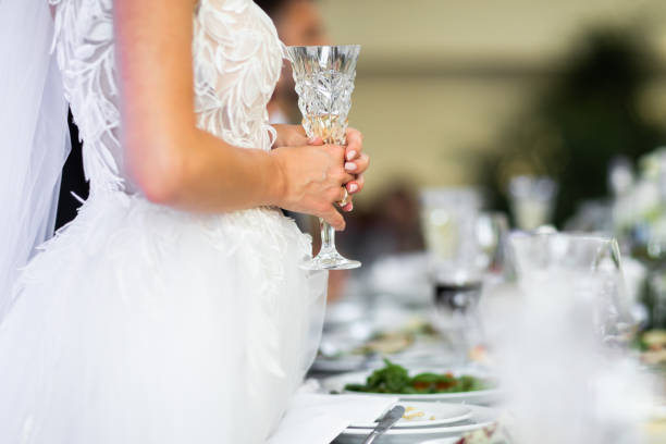 istock The bride is standing at the table and holding a glass. Table on the background. 1243246365