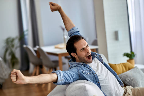 istock Young exhausted man yawning while relaxing on the sofa. 1243247319