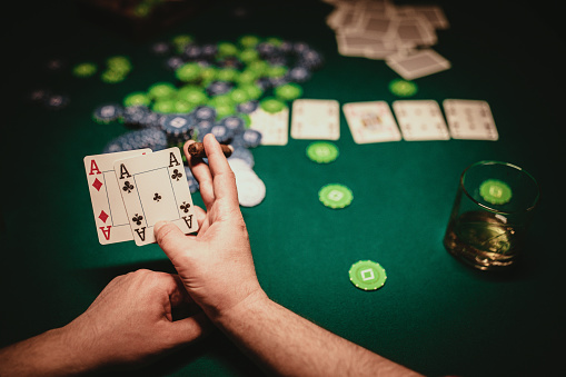 One man, gentleman playing poker in dark room at night, man holding two aces.