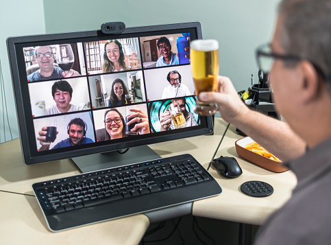 Great example of how technology can facilitate social distance during crises that require staying at home.   Case of during pandemic isolation by COVID-19. Friends drinking and toasting in a happy meeting by computer.